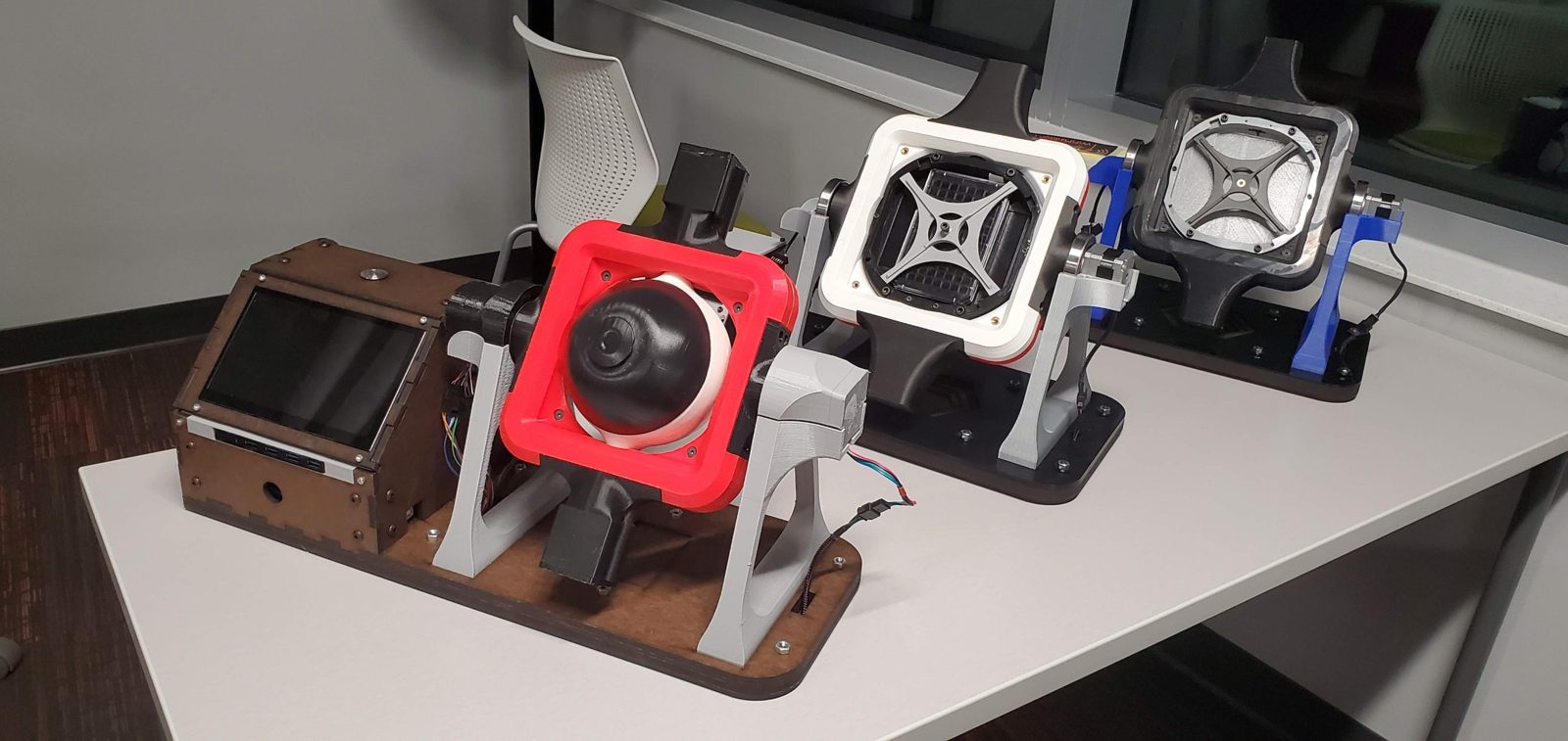 Three early SciSpinner clinostats side by side, each with a different frame and sample holder